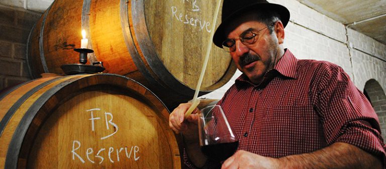 Schonender Weinausbau im Keller - Gotthard Schier mit einem Glas Piwi-Wein in der Hand